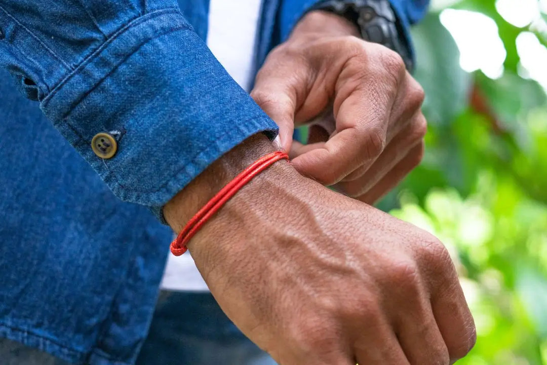 Man tying minimalist wax nylon red string bracelet on wrist – Everyday protection, surfer style