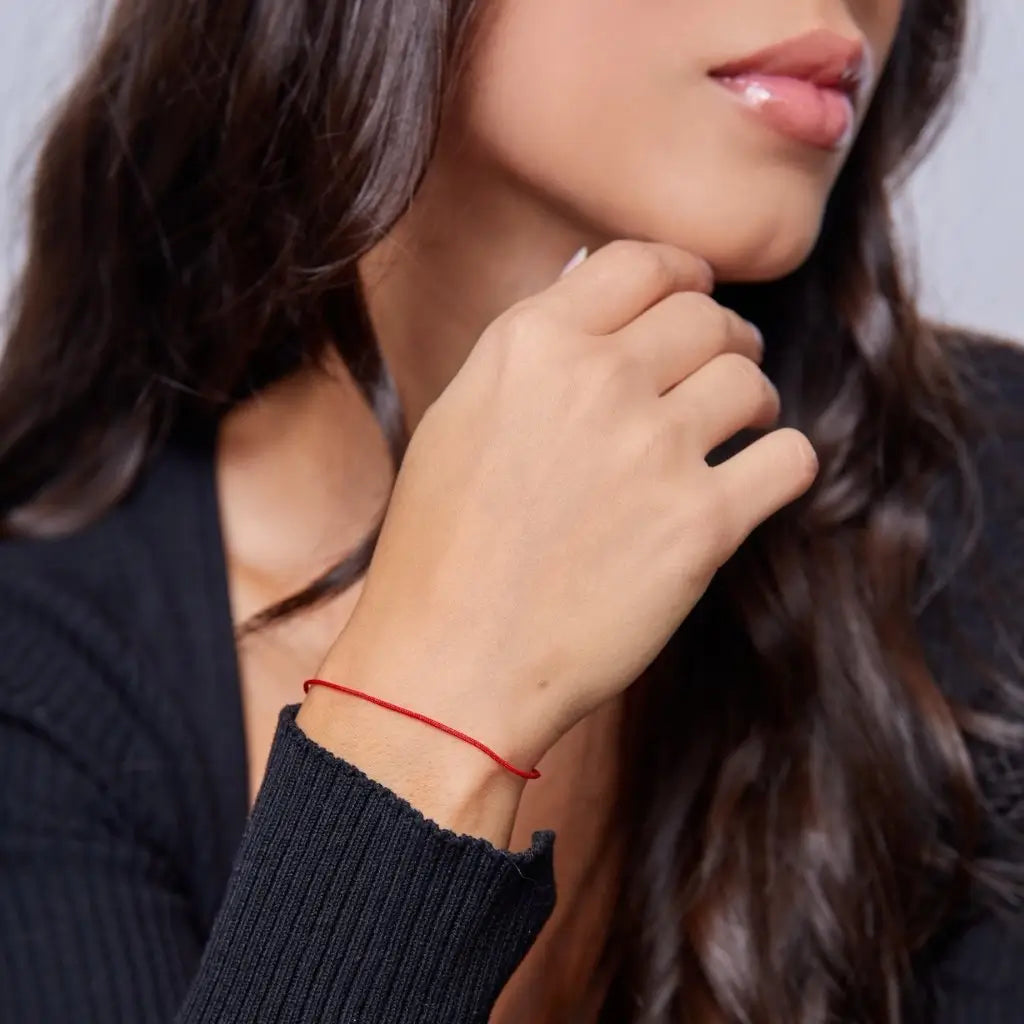 woman wearing a classic red string bracelet with a 14K solid gold clasp on their wrist - Luck Strings
