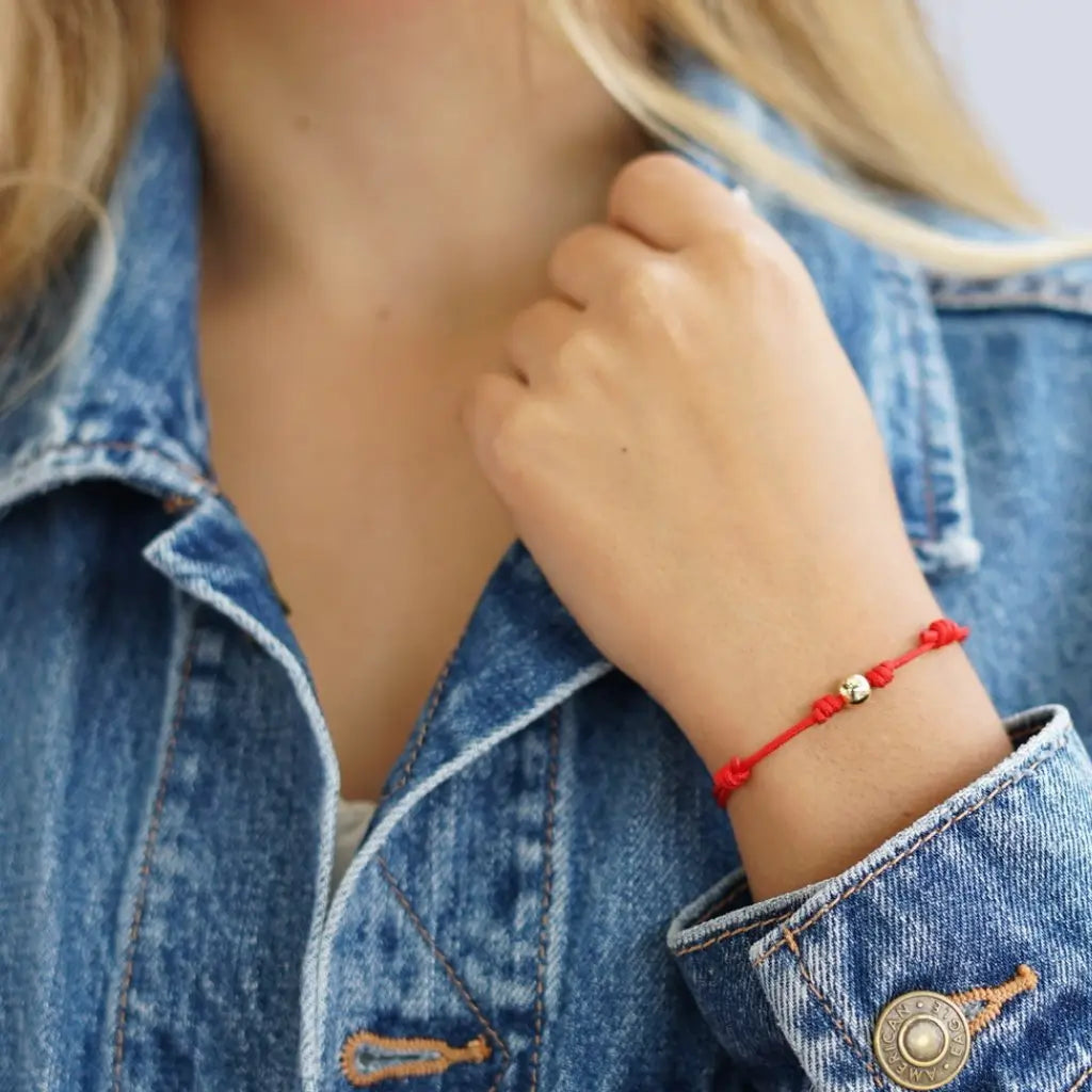 Women showcasing a black string bracelet with 14K yellow gold bead - Luck Strings