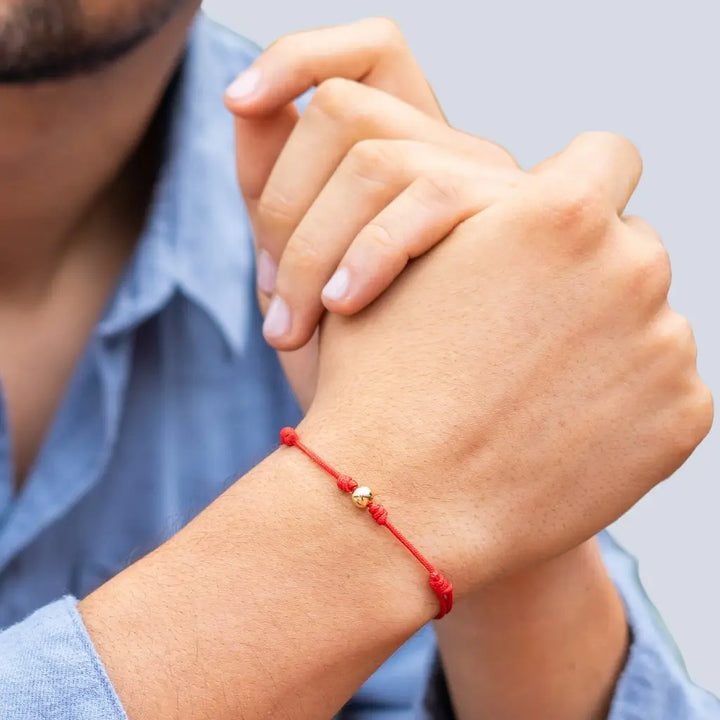 Man showcasing a red string bracelet with 14K yellow gold bead - Luck Strings