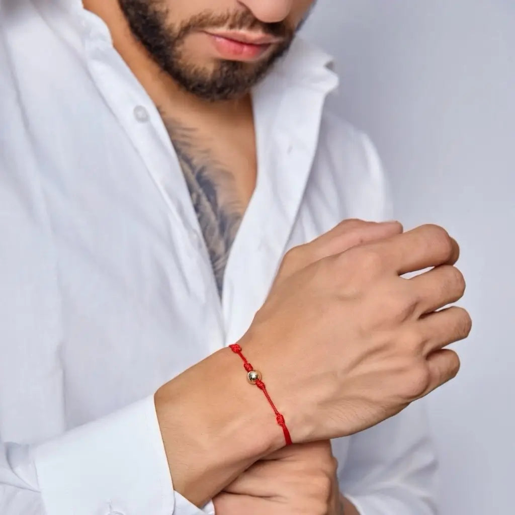 Man showcasing a red string bracelet with 14K yellow gold bead - Luck Strings