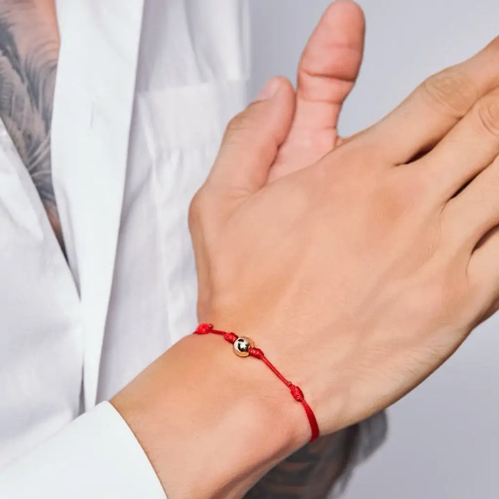 Man showcasing a black string bracelet with 14K yellow gold bead - Luck Strings