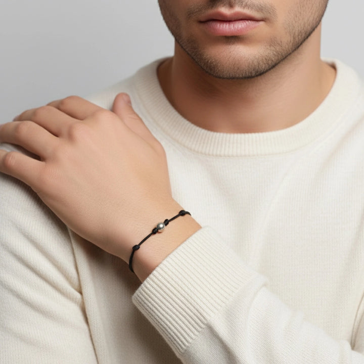 Person wearing a black bracelet on a plain background