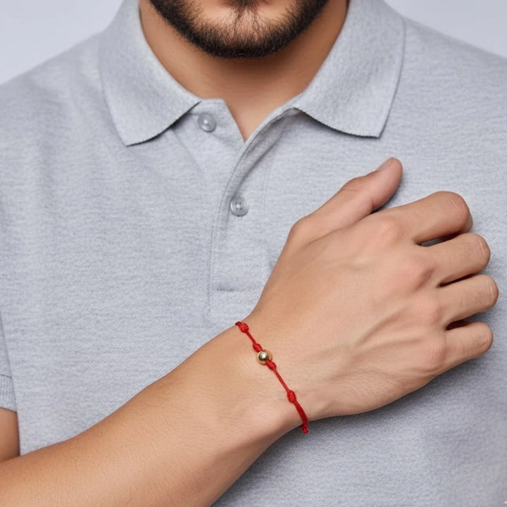 Person wearing a red bracelet on a plain background