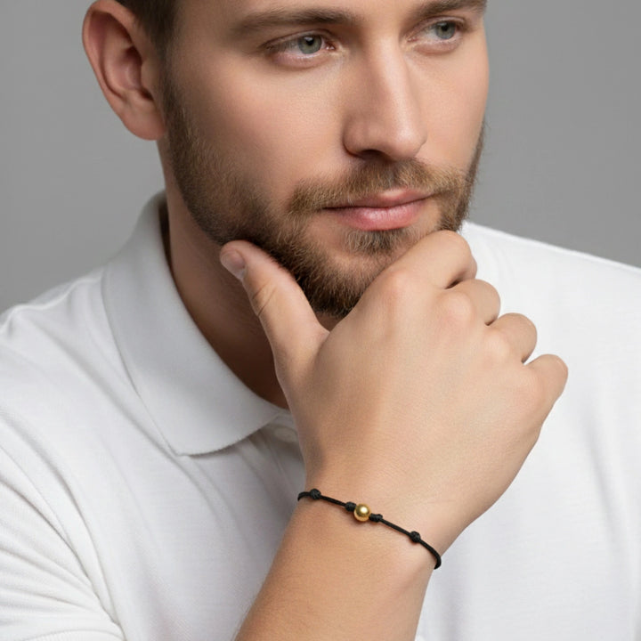 Man wearing a white polo shirt with a black bracelet on his wrist.