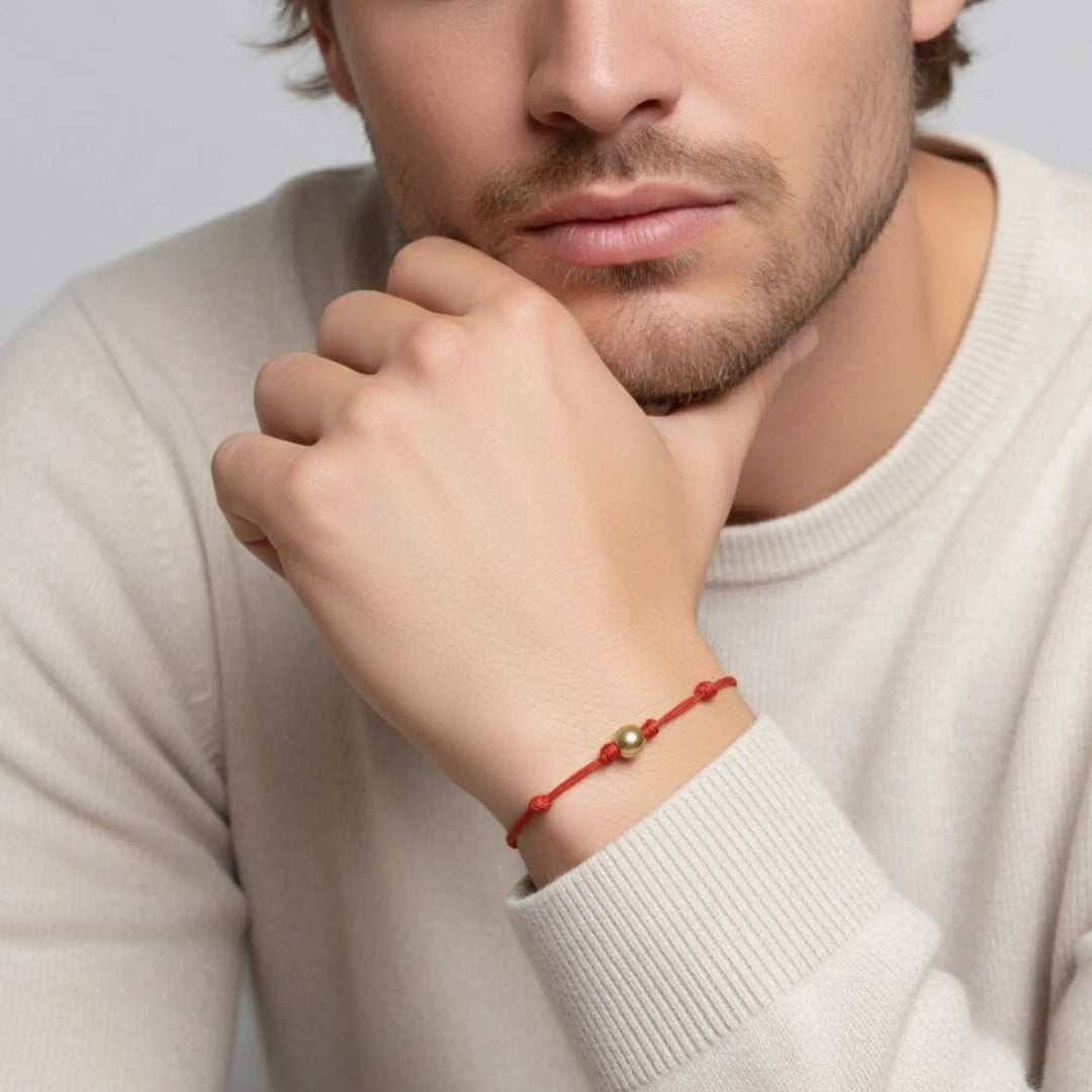 Men wearing a red solid gold bead bracelet on a plain background