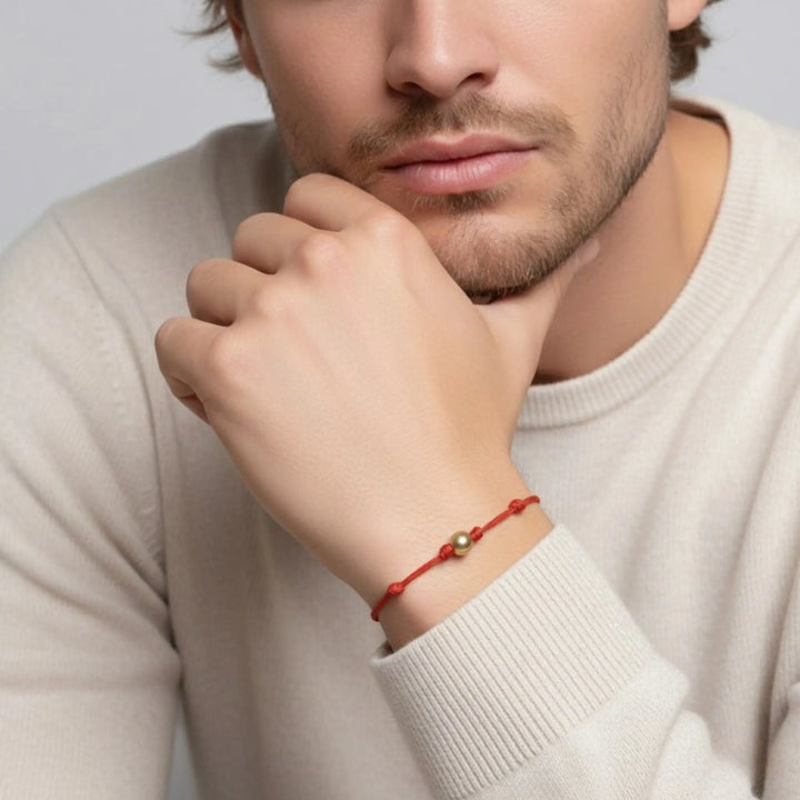 Men wearing a red solid gold bead bracelet on a plain background