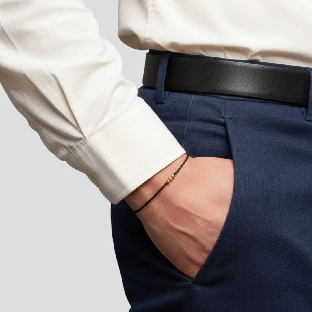 Person wearing a white shirt and navy pants with a black belt on a light gray background