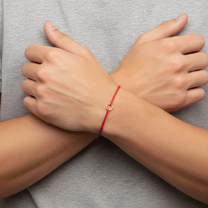Red string bracelet on a wrist with a gray background
