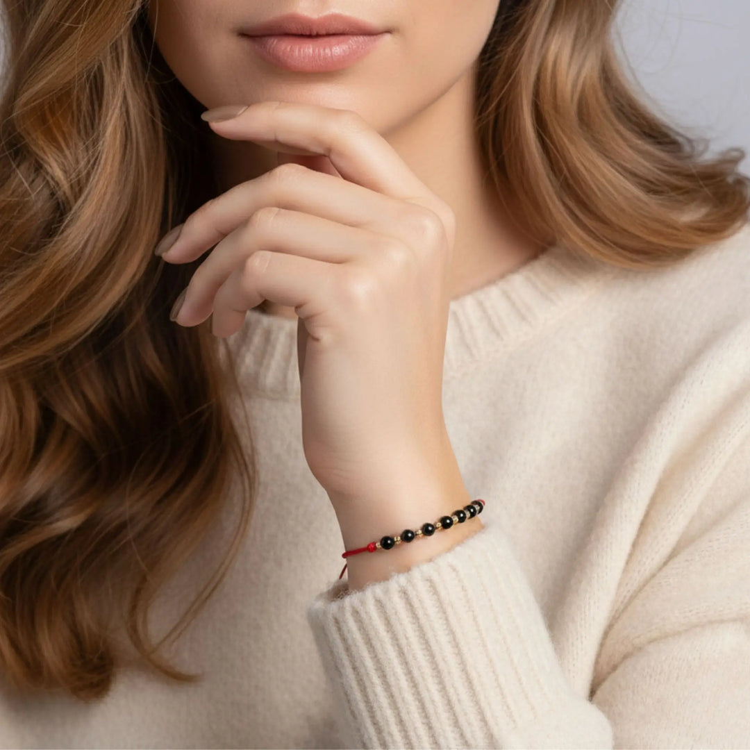 Close-up of a woman wearing a black tourmaline and red cord bracelet on her wrist.