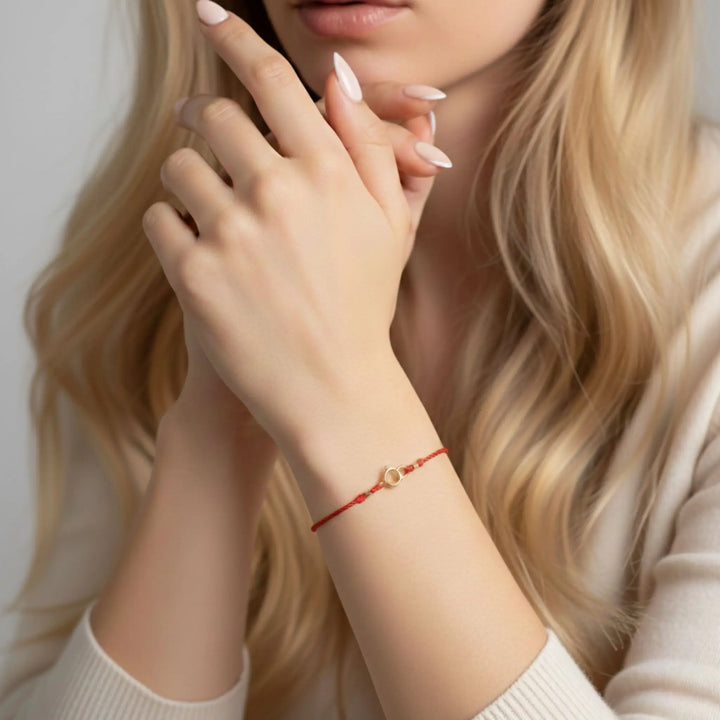 Close-up of a woman's hand wearing a red gold clasp bracelet with a neutral background