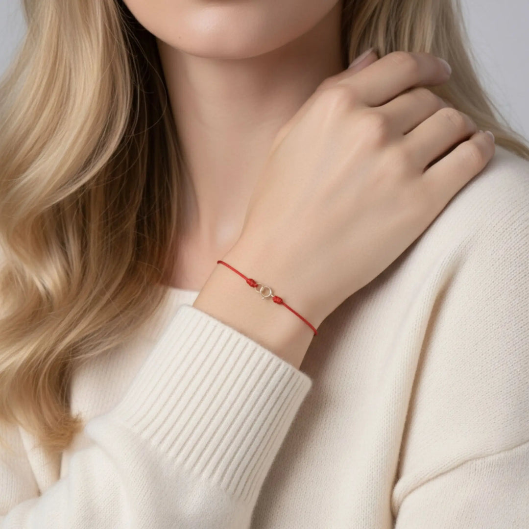 Person wearing a red bracelet on a plain background