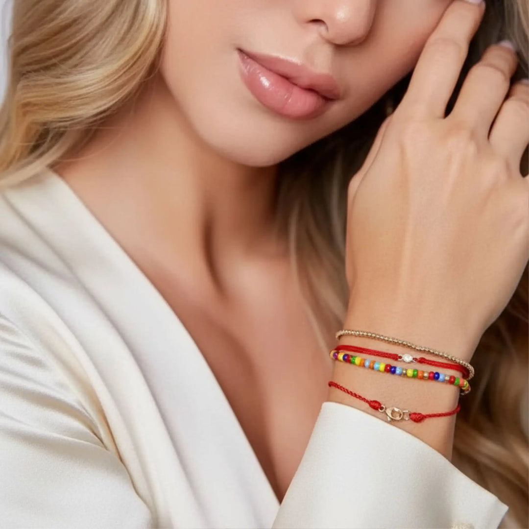 Close-up of a woman wearing colorful beaded bracelets on a neutral background
