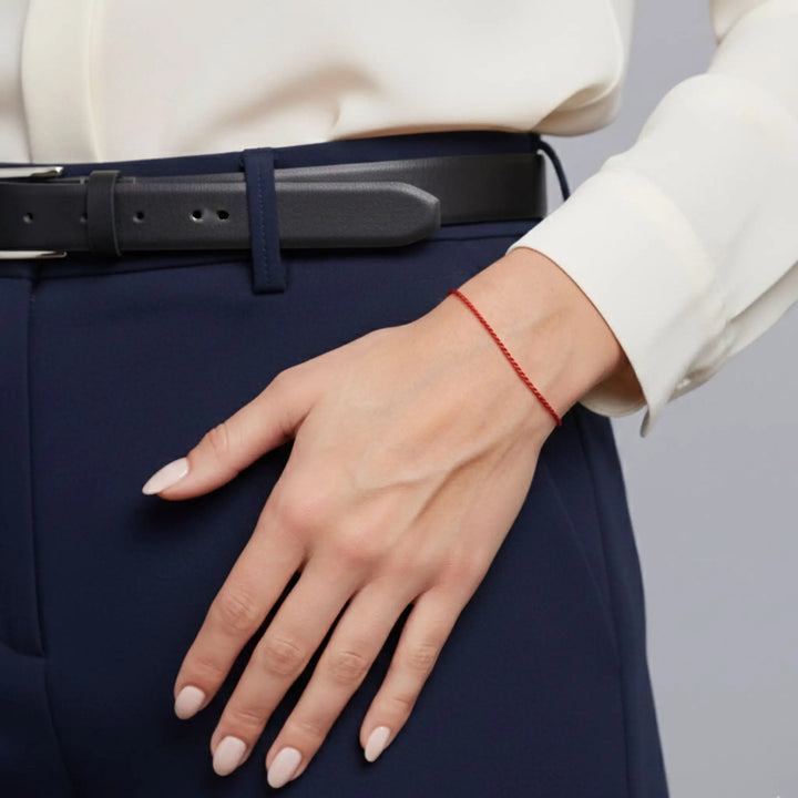 Hand wearing a rsolid gold ed bracelet with a neutral background