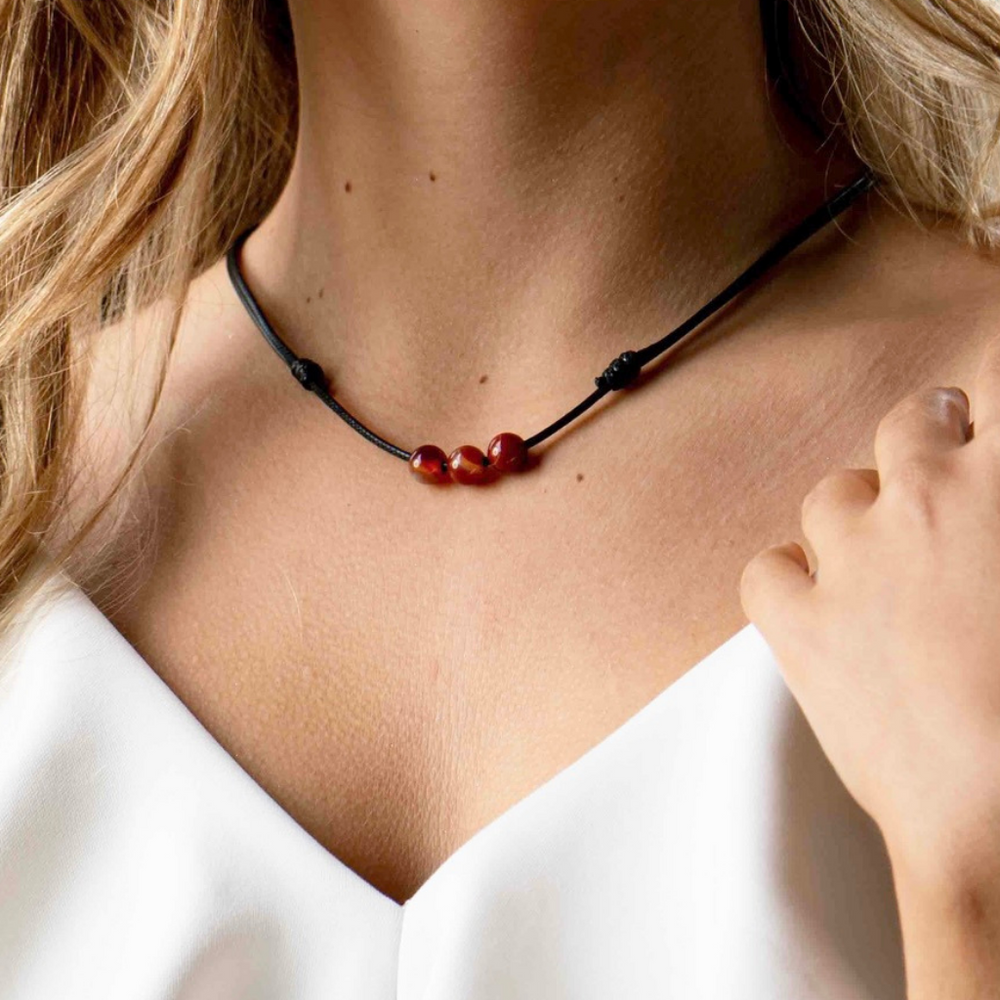 Woman elegantly wearing a Carnelian Beaded Choker, showcasing the warm, energizing hues that accentuate her stylish ensemble - Luck Strings
