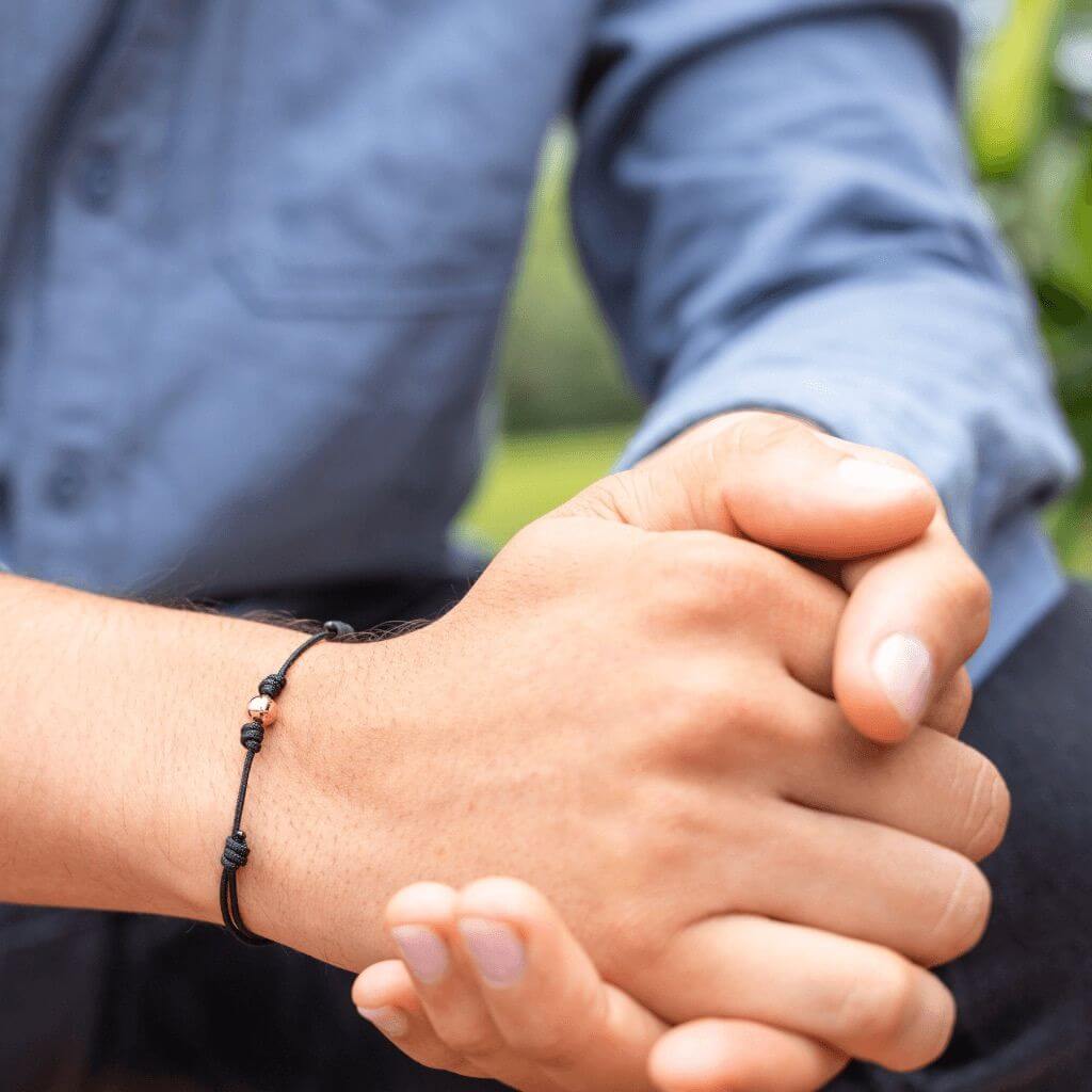 Close-up of a black string bracelet with 14K white gold beads on a male wrist - Luck Strings