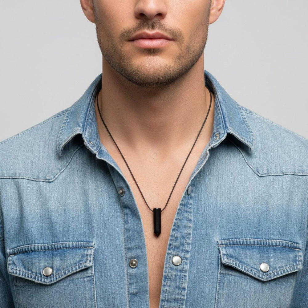 Man wearing a blue denim shirt with a black necklace against a gray background
