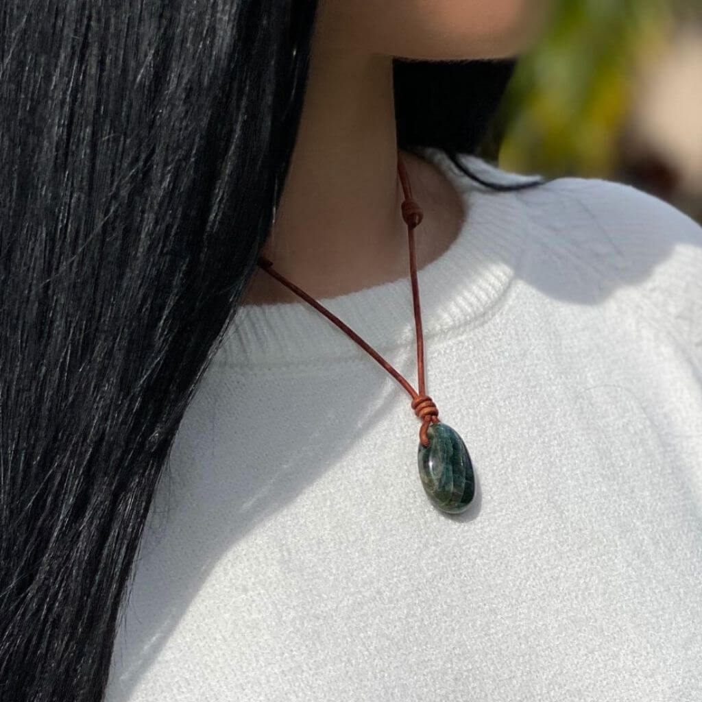 Close-up of Luck Strings blue-green apatite stone pendant on a distressed brown leather cord.