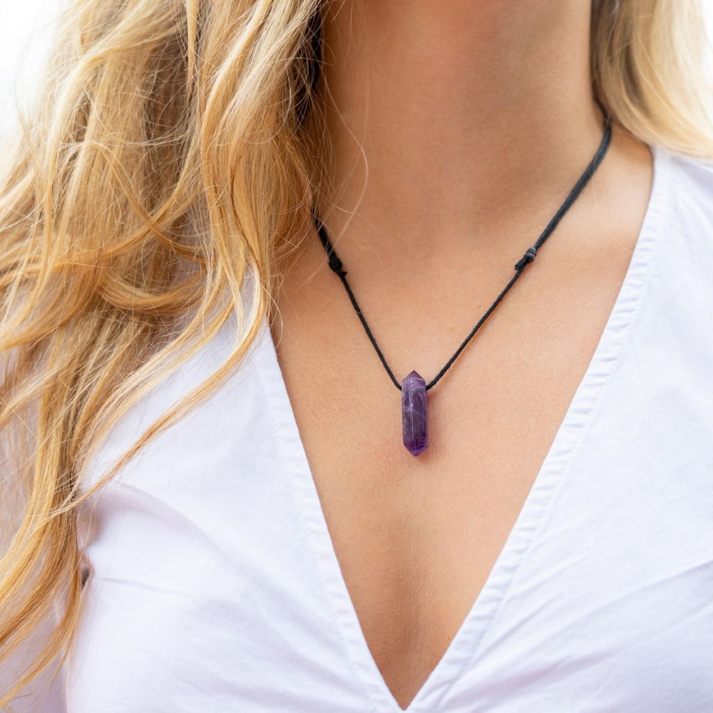 Woman elegantly wearing the Unisex Amethyst Crystal Point Necklace, symbolizing peace and style - Luck Strings.