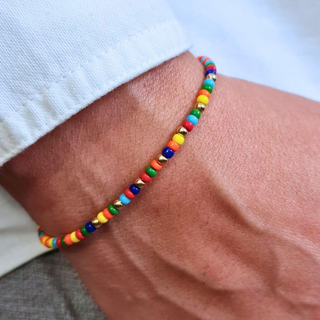 Man displaying a 14K Gold Rainbow Beaded Bracelet on his wrist, showcasing its unisex and elegant style - Luck Strings