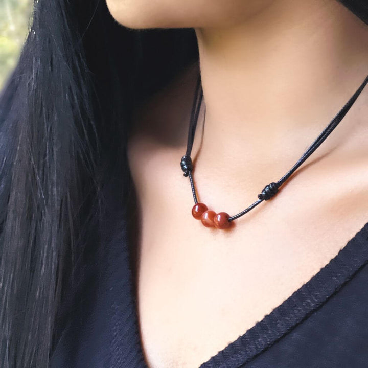 Woman elegantly wearing a Carnelian Beaded Choker, showcasing the warm, energizing hues that accentuate her stylish ensemble - Luck Strings