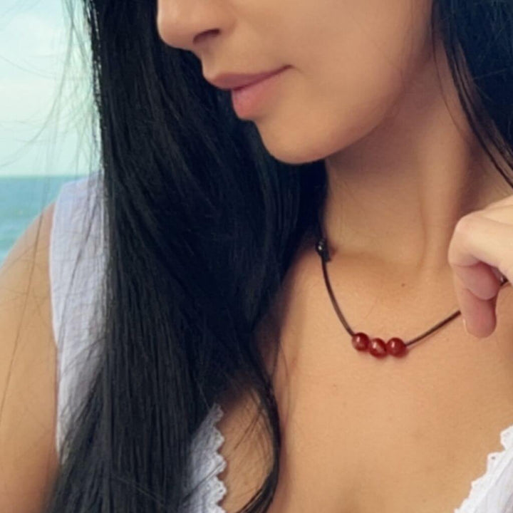Woman elegantly wearing a Carnelian Beaded Choker, showcasing the warm, energizing hues that accentuate her stylish ensemble - Luck Strings