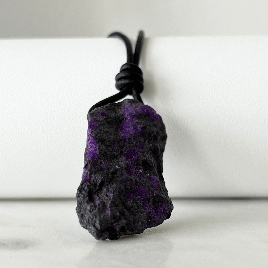 A one-of-a-kind Raw Sugilite Gemstone Pendant showcasing its distinctive deep purple color, suspended from a sleek cord, symbolizing spiritual growth and emotional healing - Luck Strings.