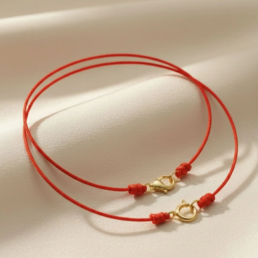 Red cord necklace with gold clasp on a beige background