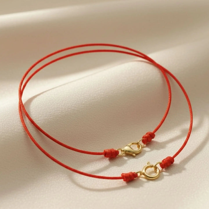 Red cord necklace with gold clasp on a beige background