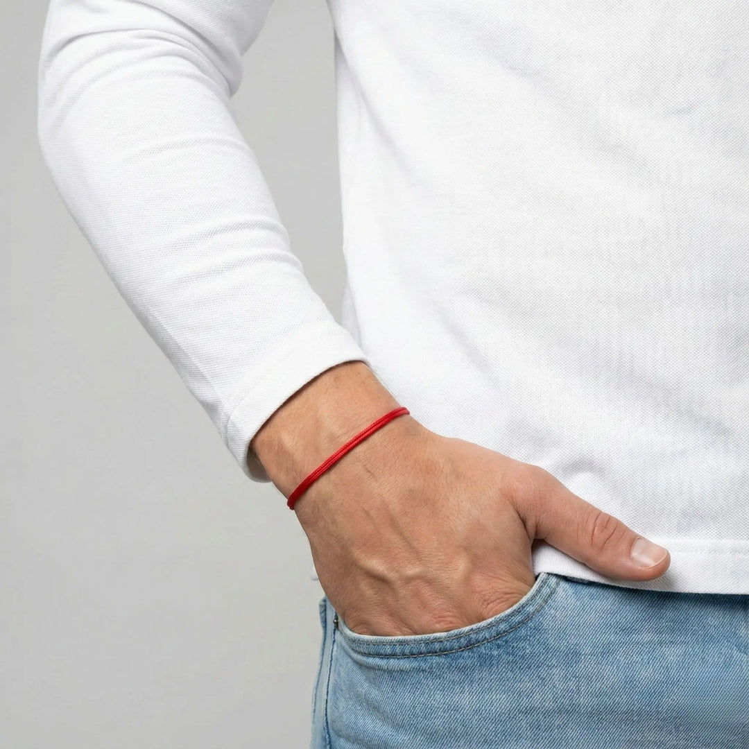 Person wearing a red bracelet on a plain background