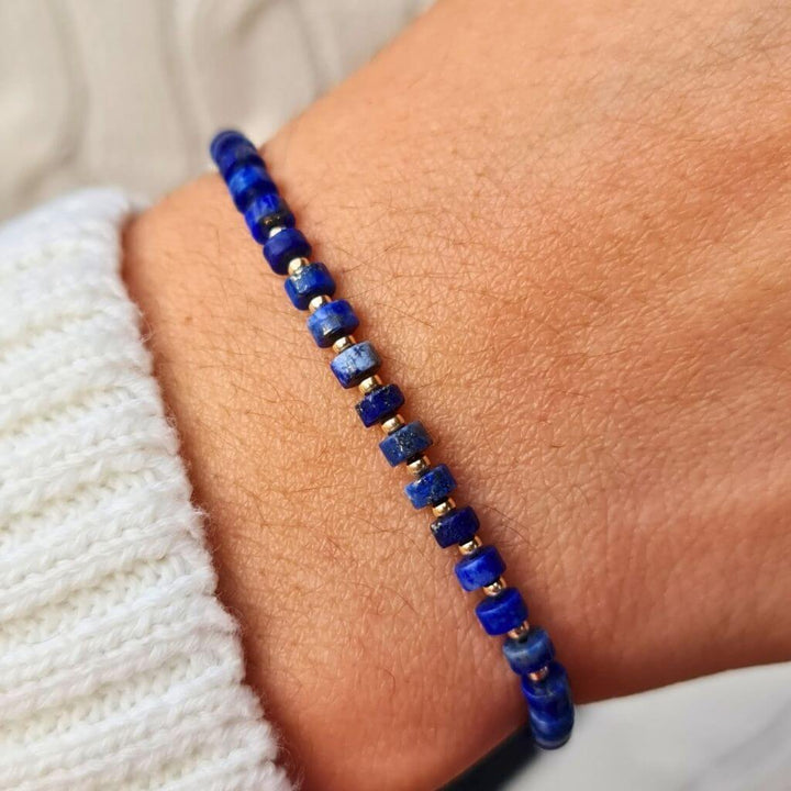 Close-up image of the Lapis Lazuli Cylinder & 14K Gold Minimalist Bracelet, showcasing its elegant design with deep blue lapis lazuli beads and sparkling 14K gold accents, embodying sophisticated simplicity - Luck Strings