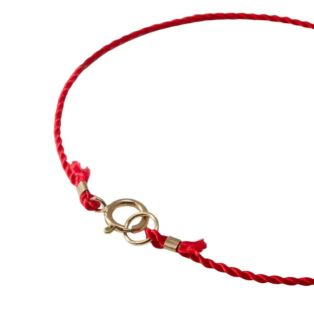 Luck Strings red string bracelet with 14k solid yellow gold clasp on a person's wrist.