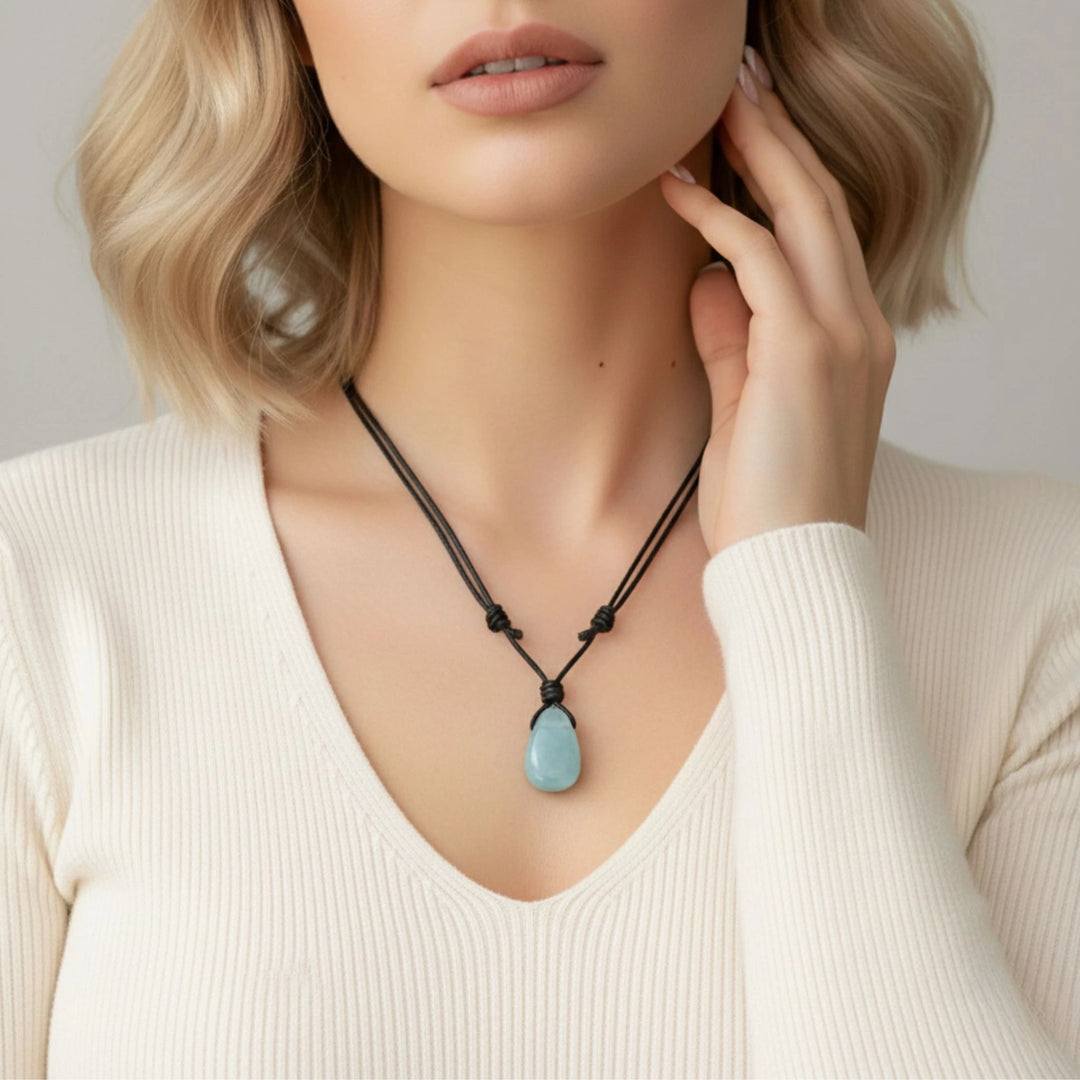 Woman wearing a necklace with a blue pendant against a neutral background