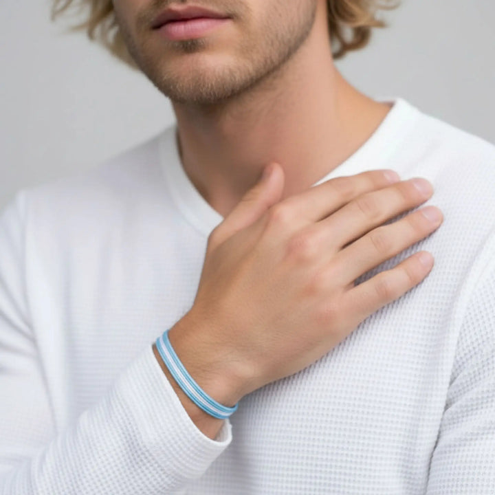 Man wearing a white shirt with a blue and white striped wristband on his left wrist.