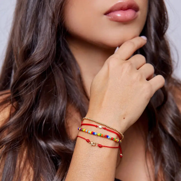 Woman displaying a 14K Gold Diamond Bezel Red String Bracelet, highlighting the elegance and powerful protection of the vibrant red string – Luck Strings
