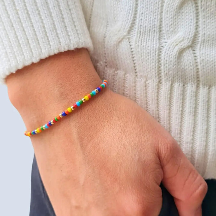 Man displaying a 14K Gold Rainbow Beaded Bracelet on his wrist, showcasing its unisex and elegant style - Luck Strings