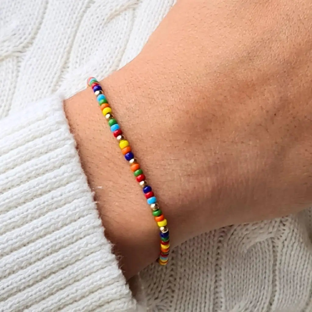 Man displaying a 14K Gold Rainbow Beaded Bracelet on his wrist, showcasing its unisex and elegant style - Luck Strings