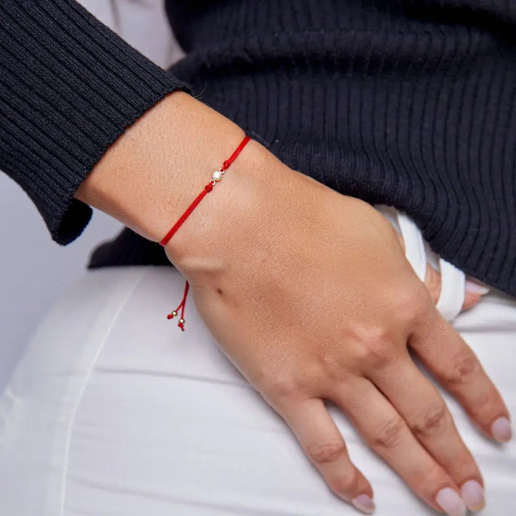 Woman displaying a 14K Gold Diamond Bezel Red String Bracelet,highlighting the elegance and powerful protection of the vibrant red string – Luck Strings