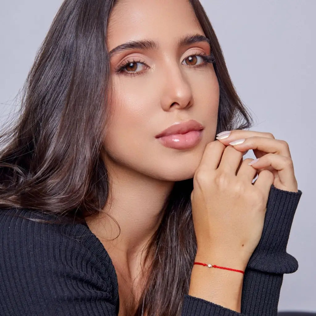 Woman displaying a 14K Gold Diamond Bezel Red String Bracelet, highlighting the elegance and powerful protection of the vibrant red string – Luck Strings