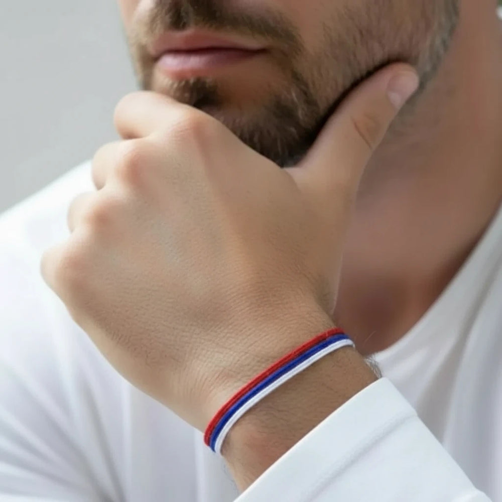 Man wearing a white, red, and blue bracelet on his wrist.