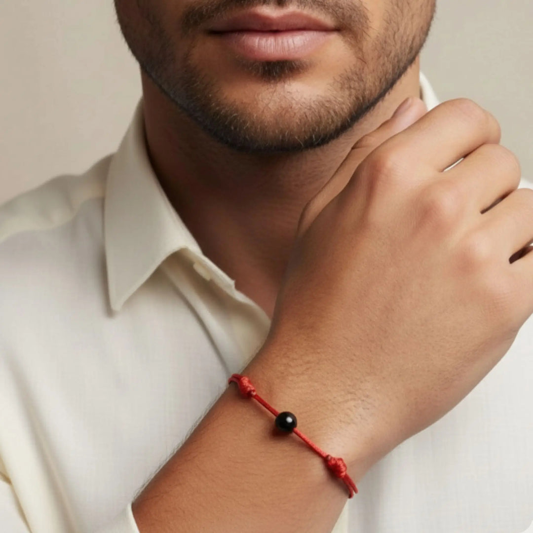 Man wearing a red bracelet with a black tourmaline bead on his wrist.