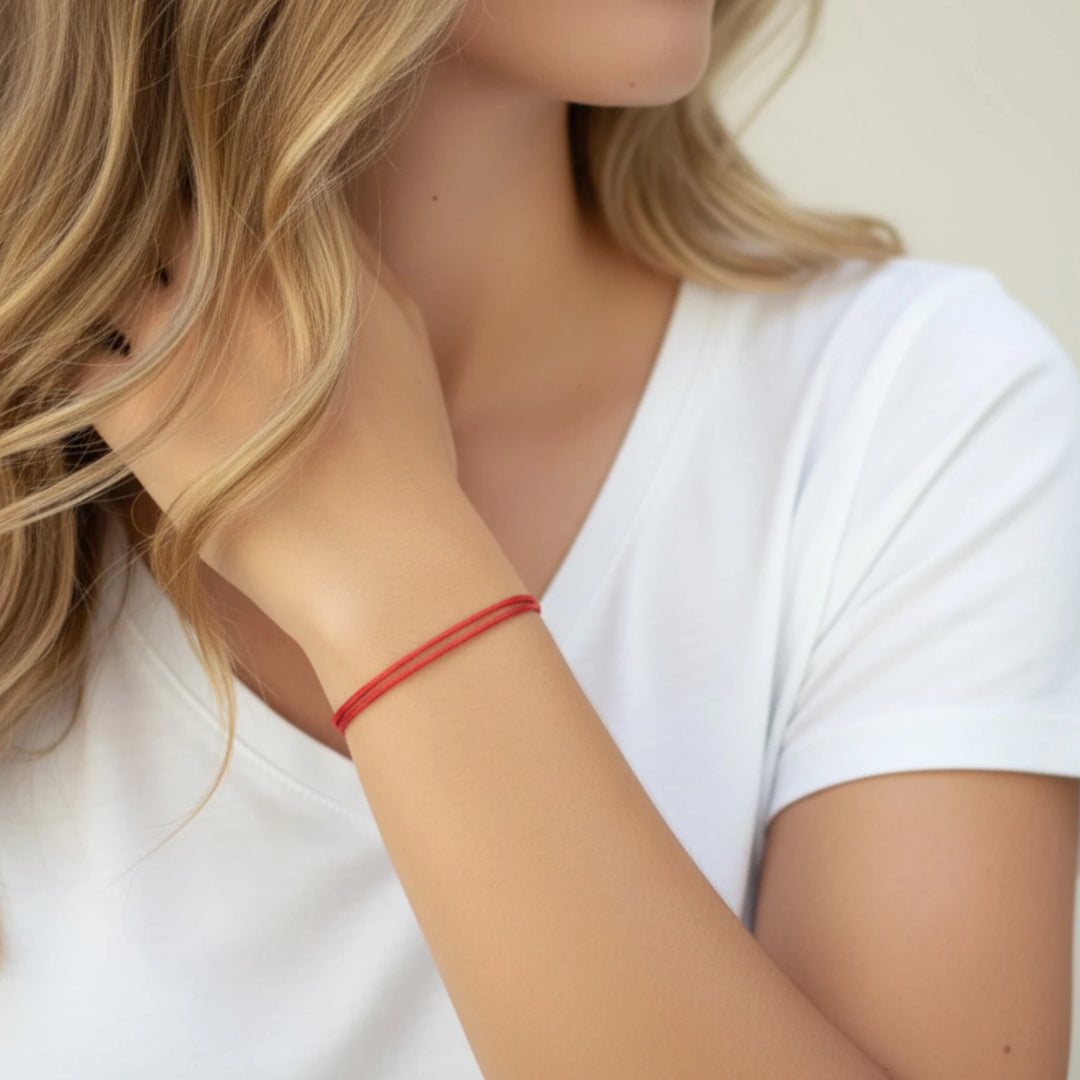 Close-up of a person wearing a red bracelet on a plain background