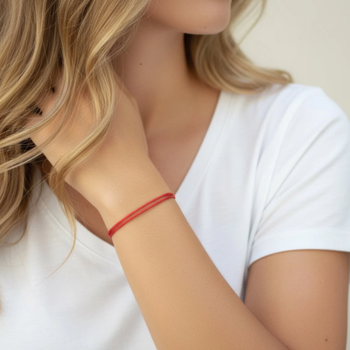 Close-up of a person wearing a red bracelet on a plain background