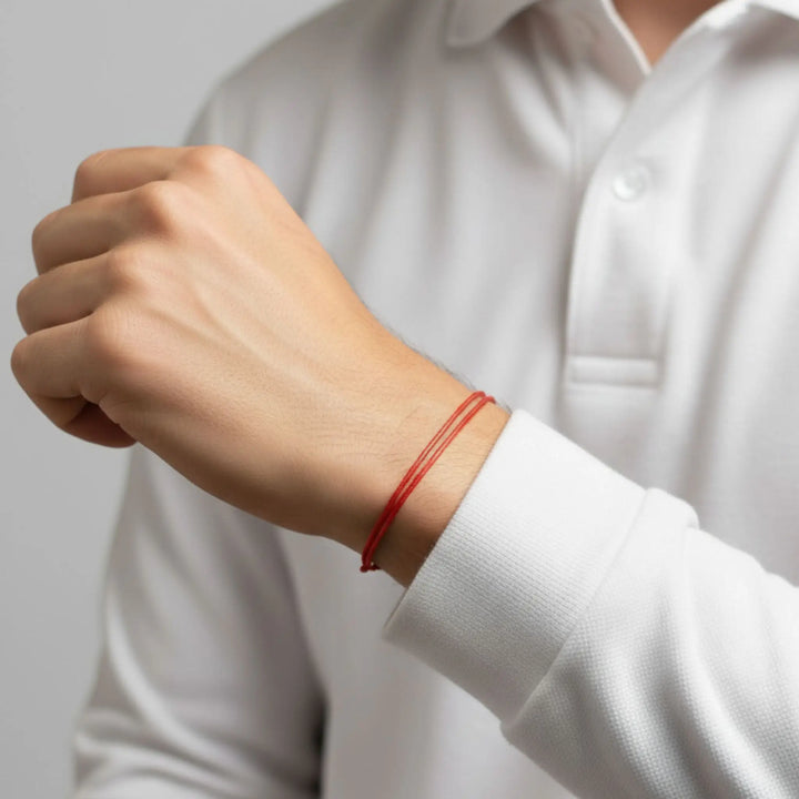 Person wearing a red bracelet on a plain background