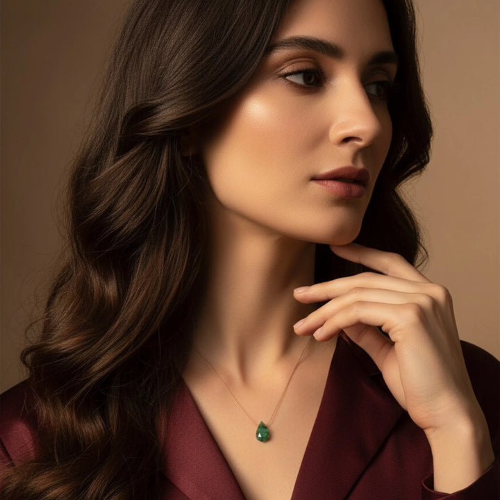 Woman wearing a green emerald necklace against a neutral background