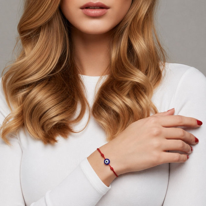 Woman wearing a red bracelet with a blue bead on a neutral background