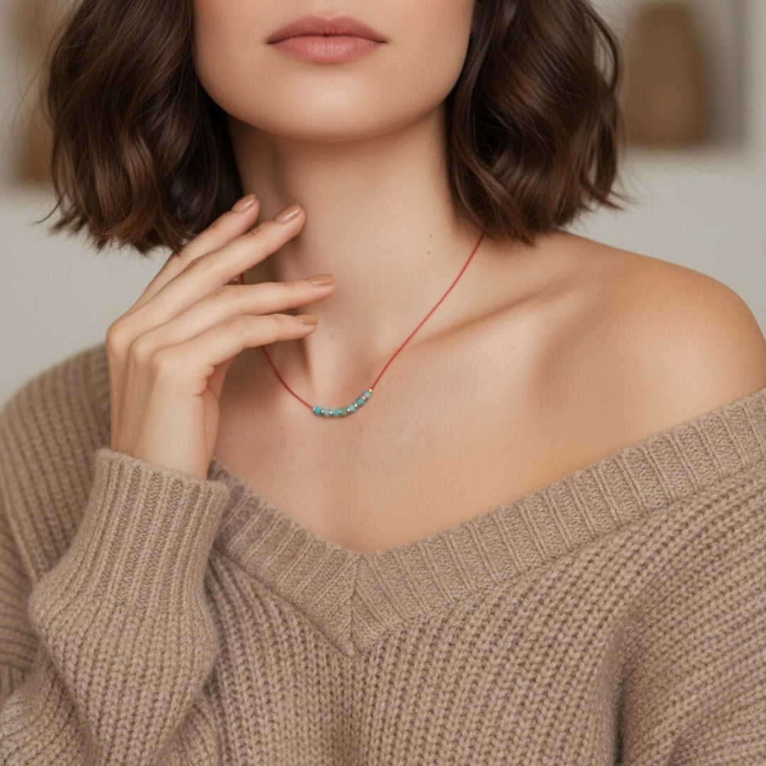 Woman wearing a turquoise necklace with a beige sweater