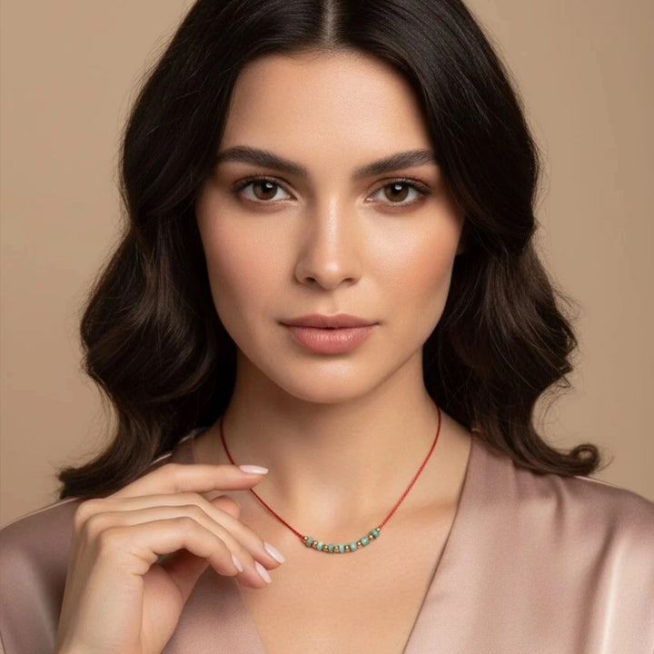 Woman wearing a red necklace with turquoise beads against a beige background