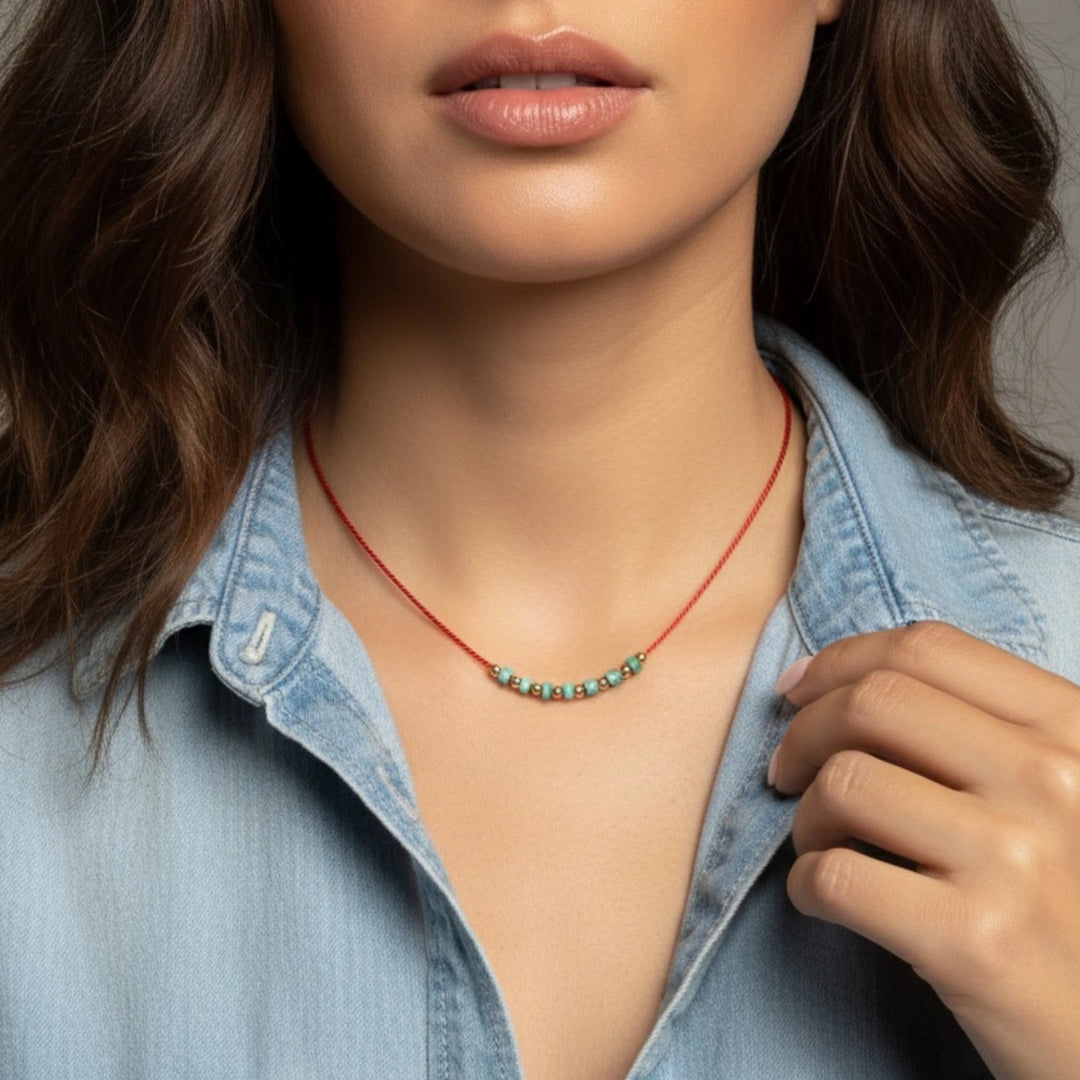 Necklace with turquoise beads worn by a person in a denim shirt.