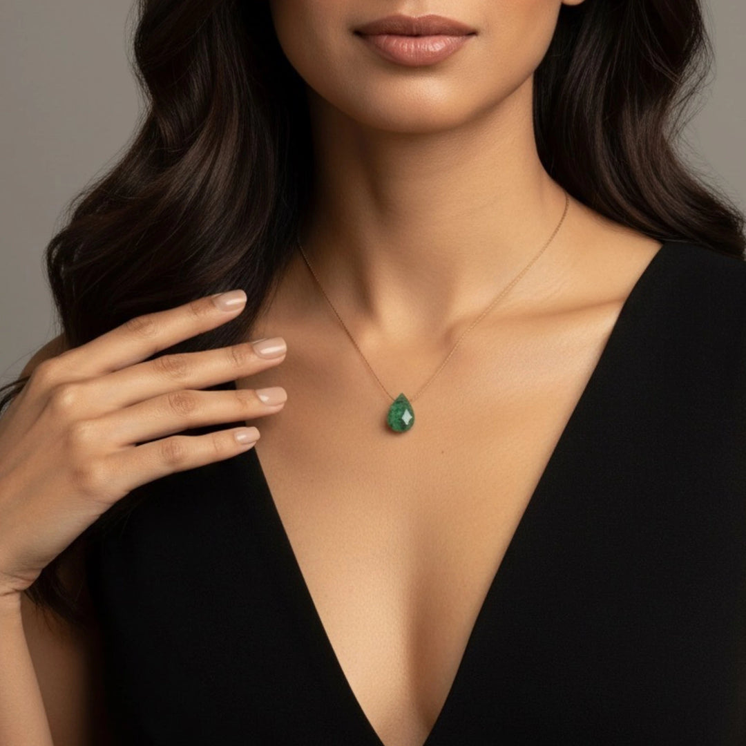 Woman wearing a green emerald necklace against a neutral background